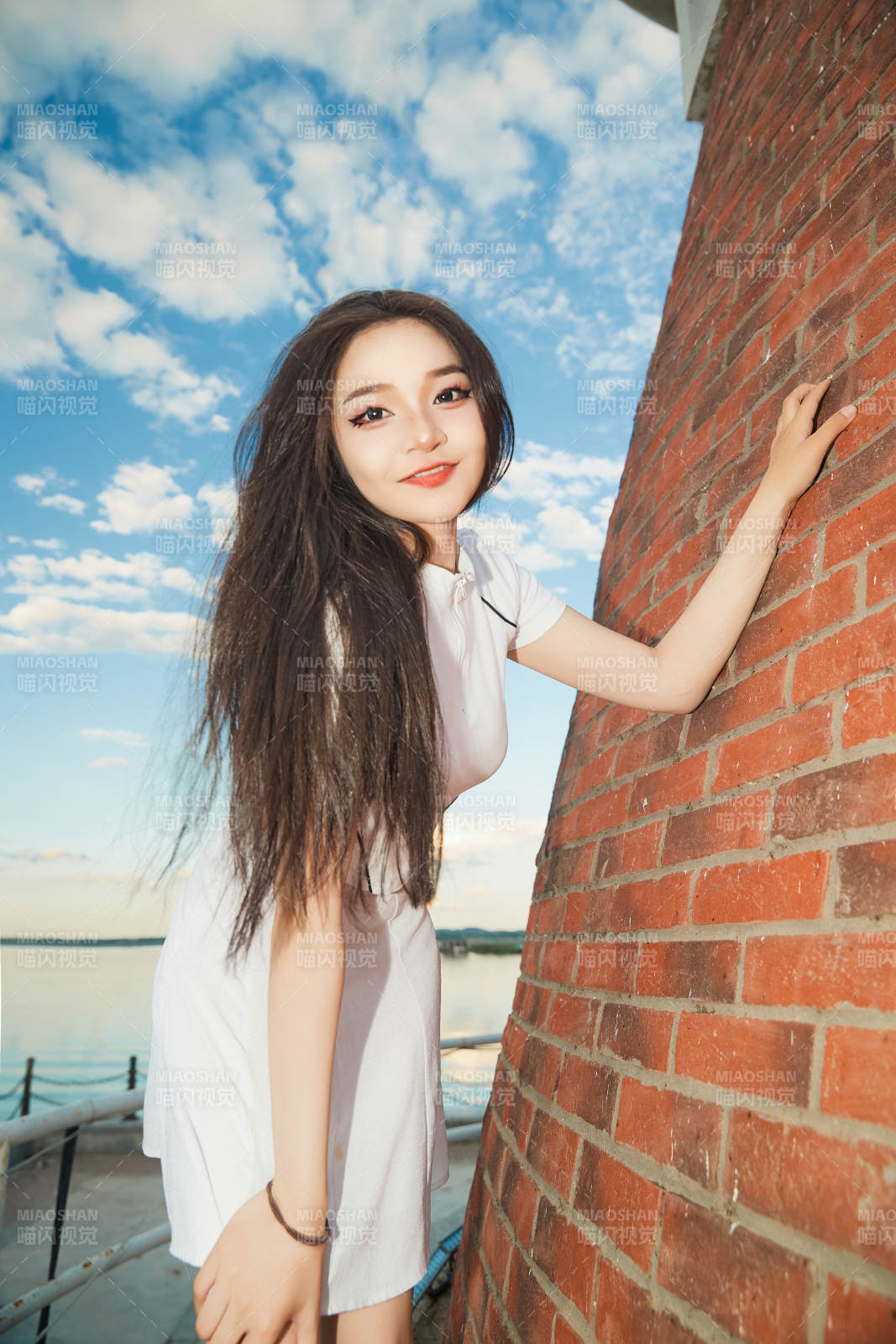 盛夏在景区湖边灯塔上拍照游玩的美女图片