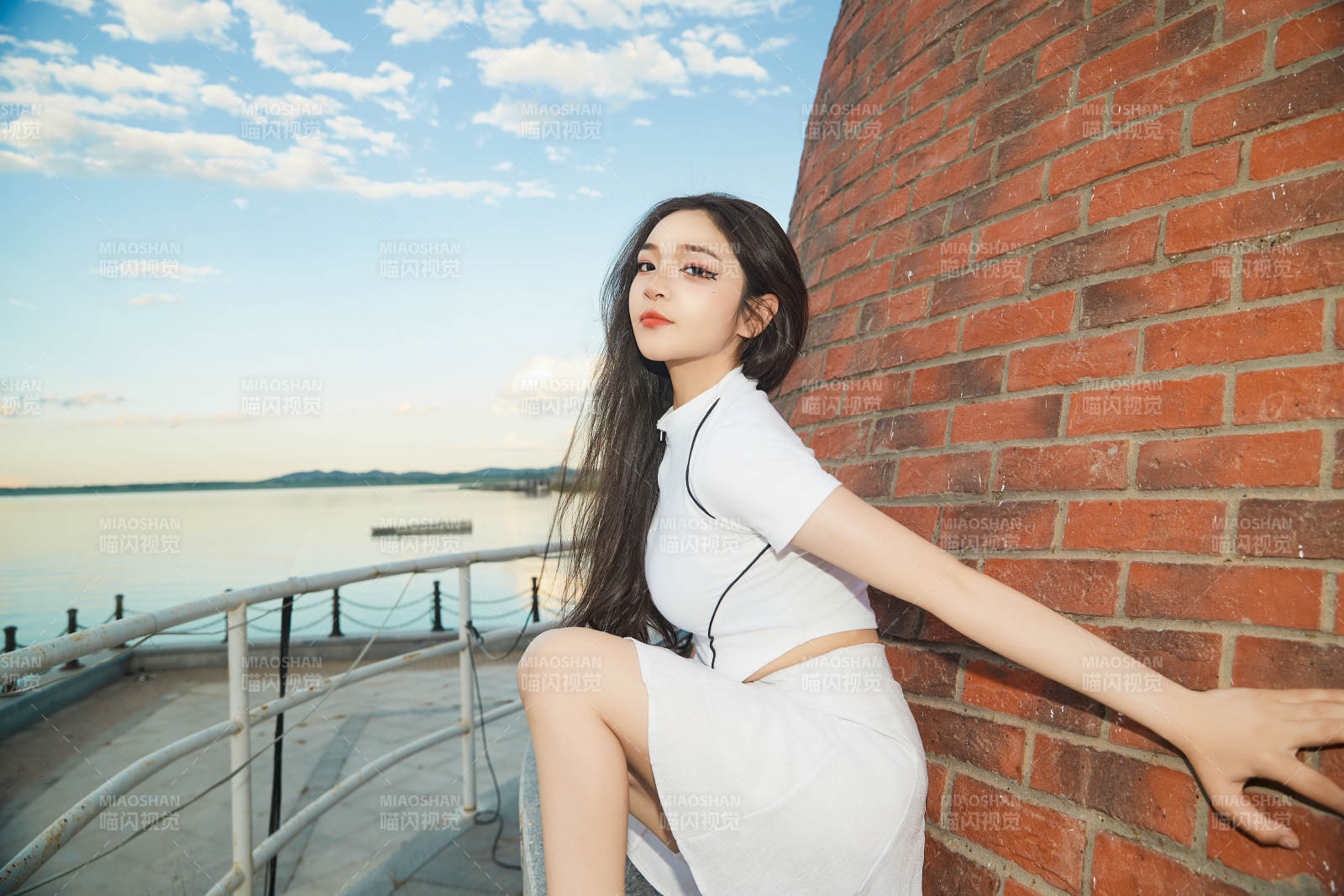 盛夏在景区湖边灯塔上拍照游玩的美女图片