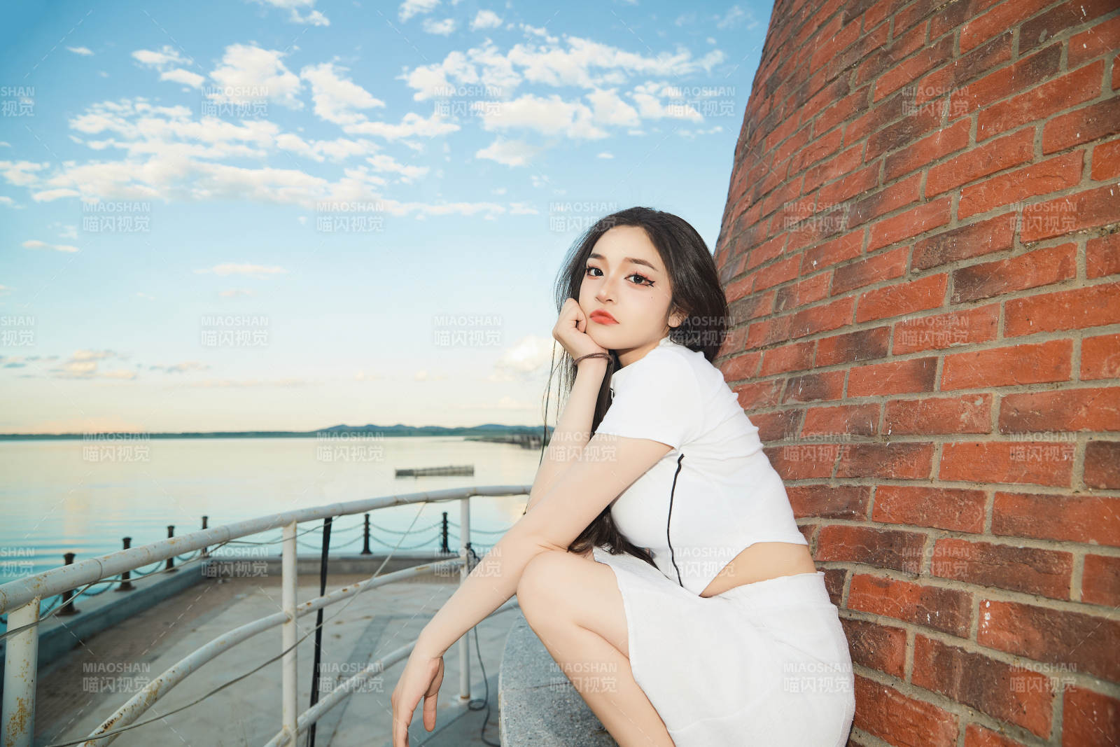 盛夏在景区湖边灯塔上拍照游玩的美女图片