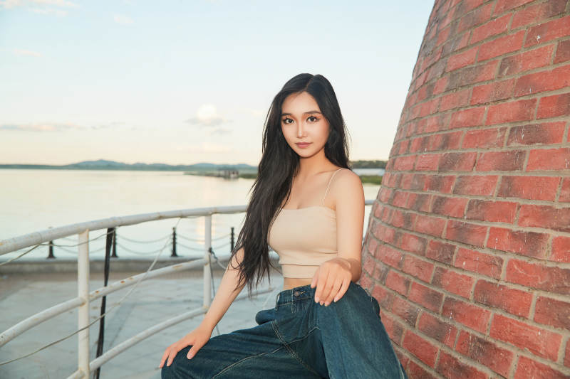 盛夏在景区湖边灯塔上拍照游玩的美女图片