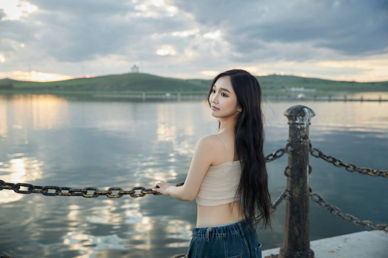 傍晚在湖边欣赏风景拍照的亚洲美女图片