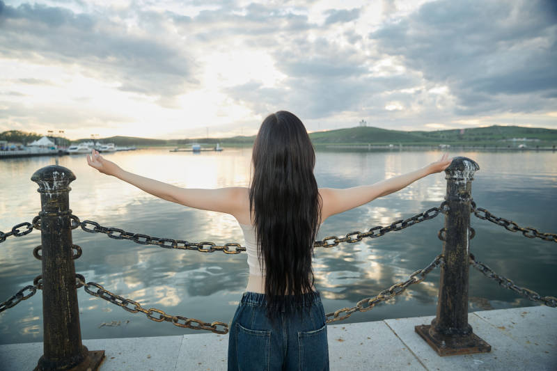 傍晚在湖边欣赏风景拍照的亚洲美女图片