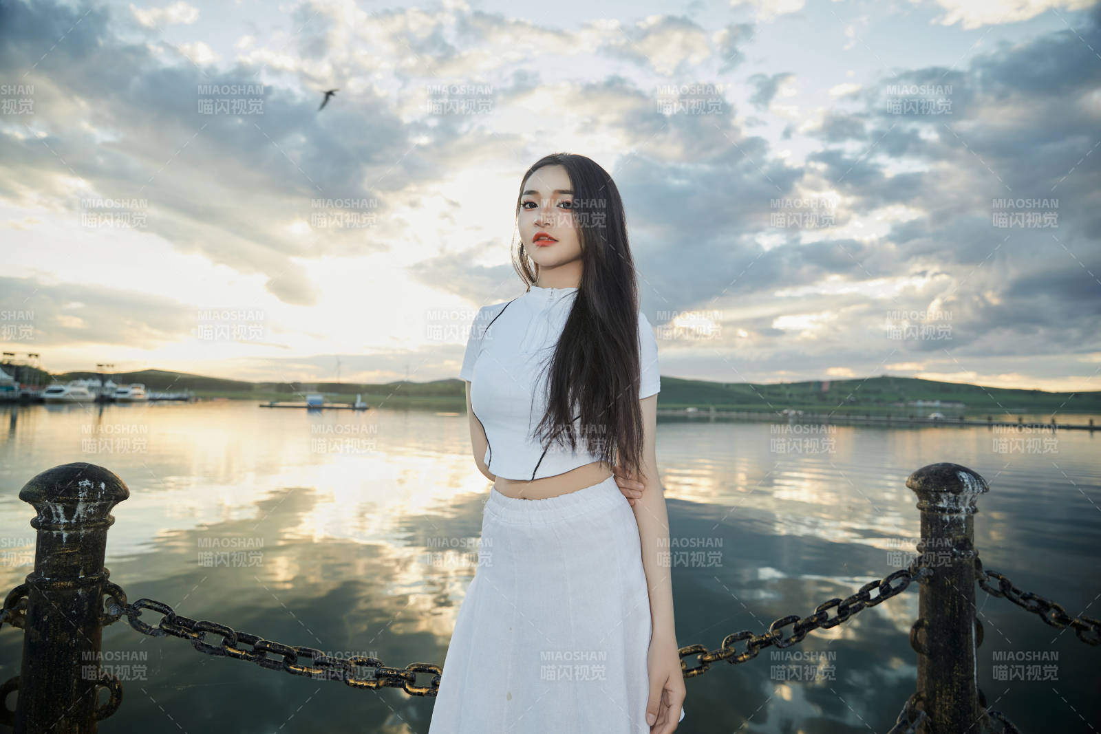 傍晚在湖边欣赏风景拍照的亚洲美女图片