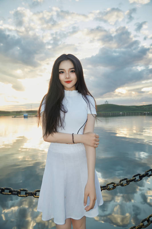 傍晚在湖边欣赏风景拍照的亚洲美女图片