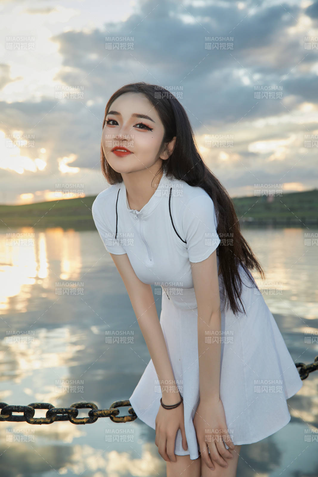 傍晚在湖边欣赏风景拍照的亚洲美女图片