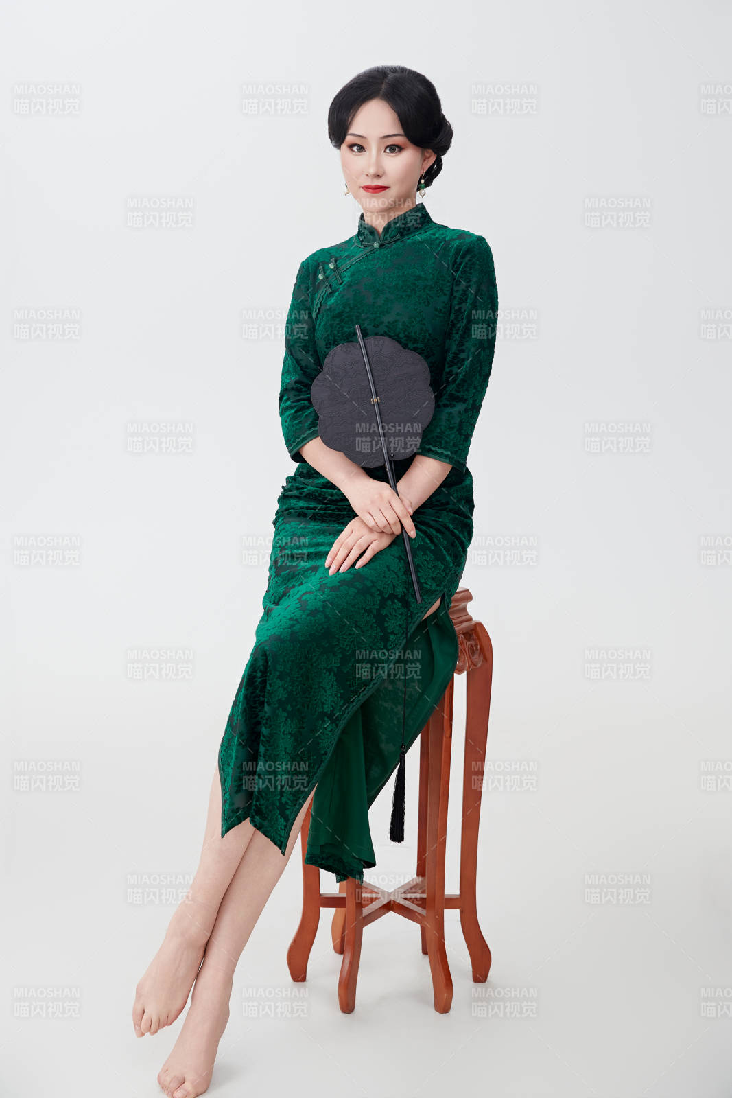 手拿纸扇身着中式旗袍坐在凳子上的美女图片