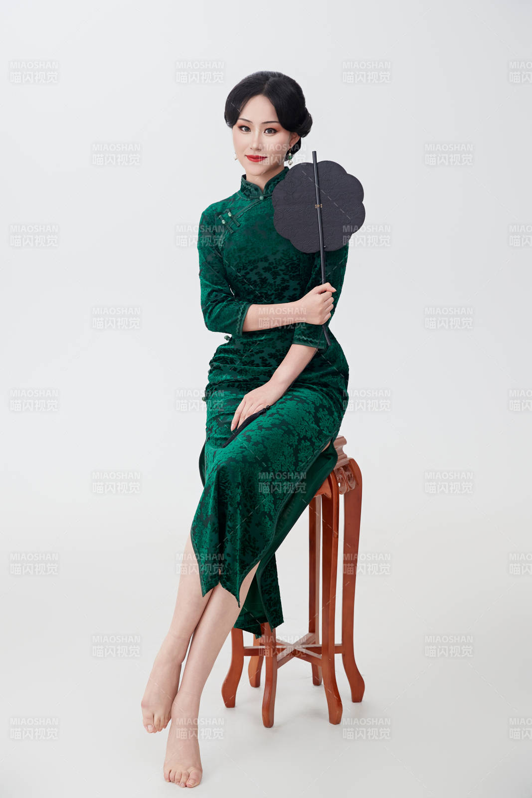 手拿纸扇身着中式旗袍坐在凳子上的美女图片