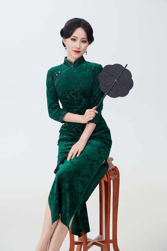 手拿纸扇身着中式旗袍坐在凳子上的美女图片