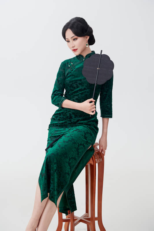 手拿纸扇身着中式旗袍坐在凳子上的美女图片