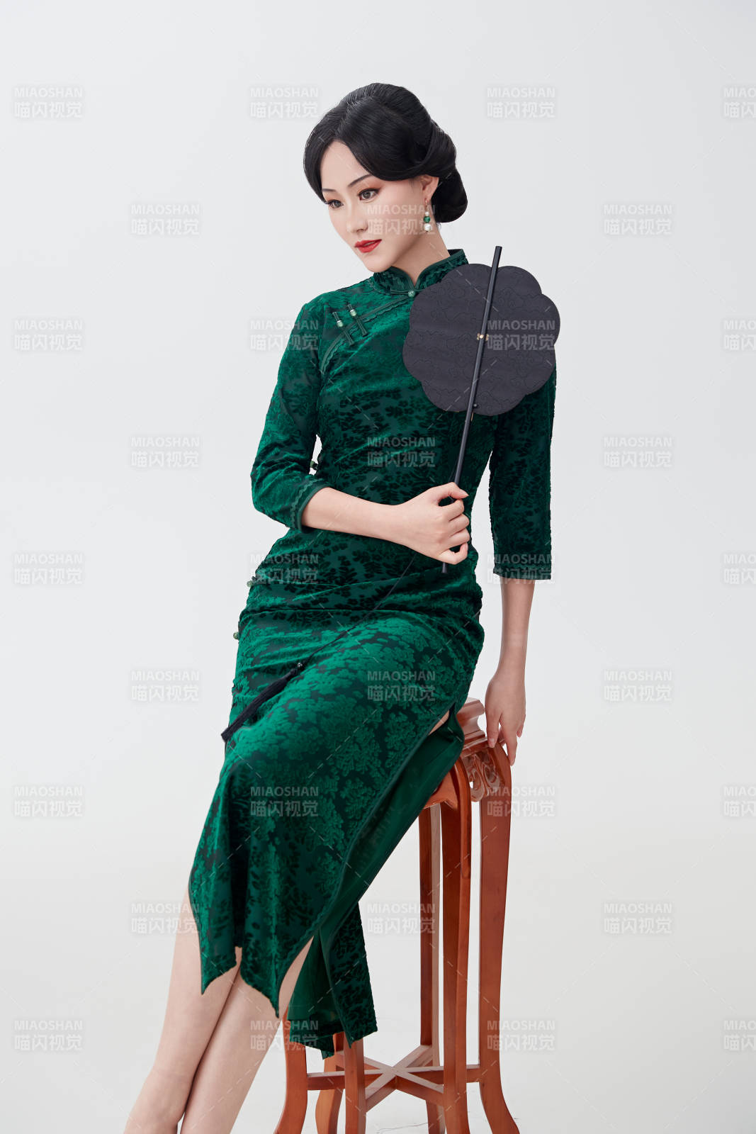 手拿纸扇身着中式旗袍坐在凳子上的美女图片