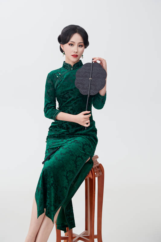手拿纸扇身着中式旗袍坐在凳子上的美女图片