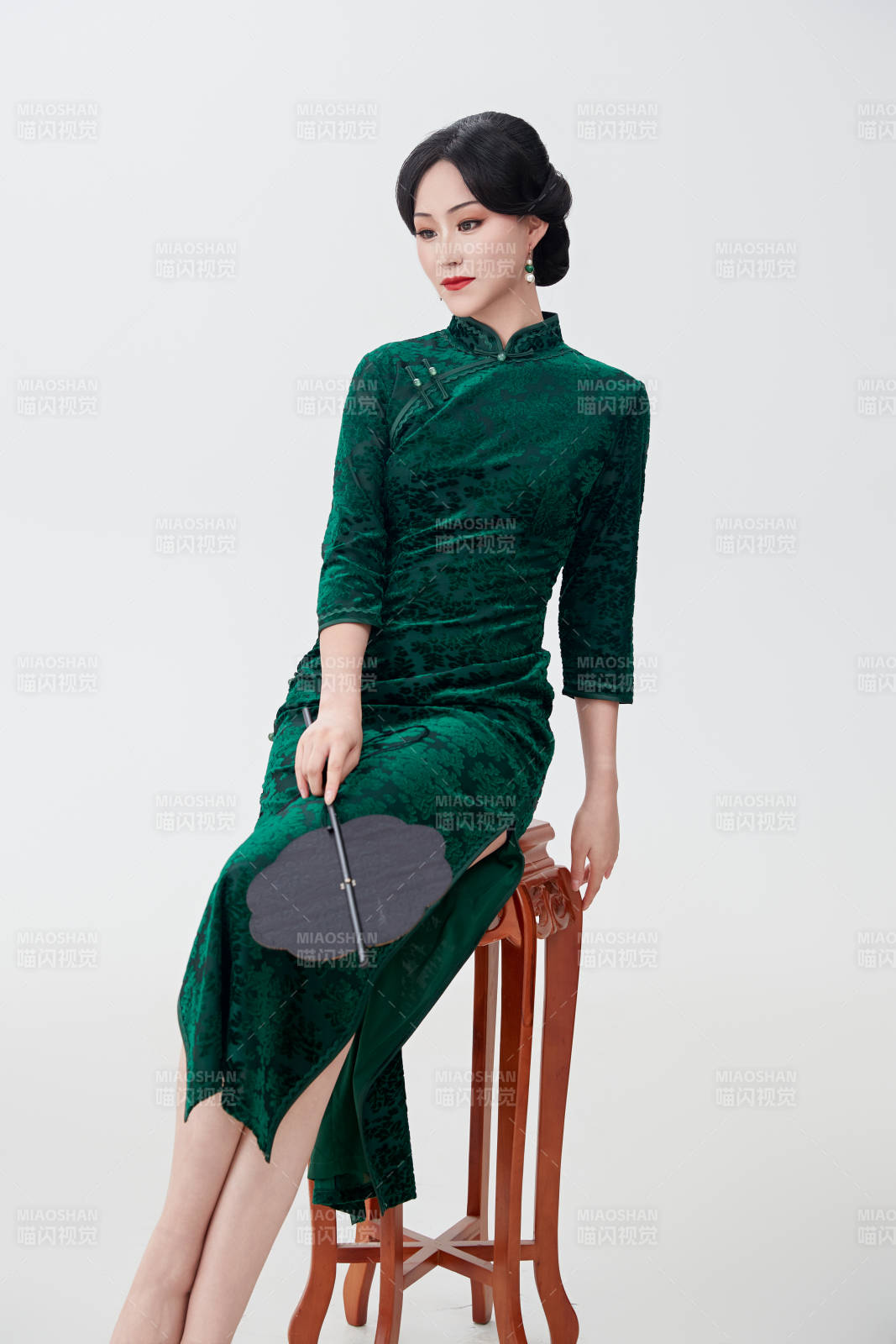 手拿纸扇身着中式旗袍坐在凳子上的美女图片