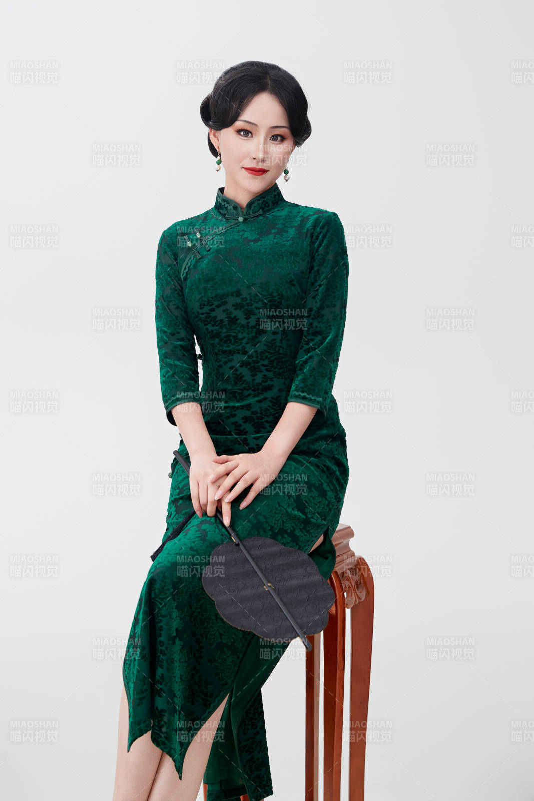 手拿纸扇身着中式旗袍坐在凳子上的美女图片