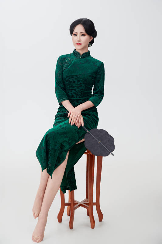 手拿纸扇身着中式旗袍坐在凳子上的美女图片