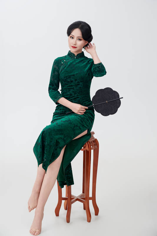 手拿纸扇身着中式旗袍坐在凳子上的美女图片