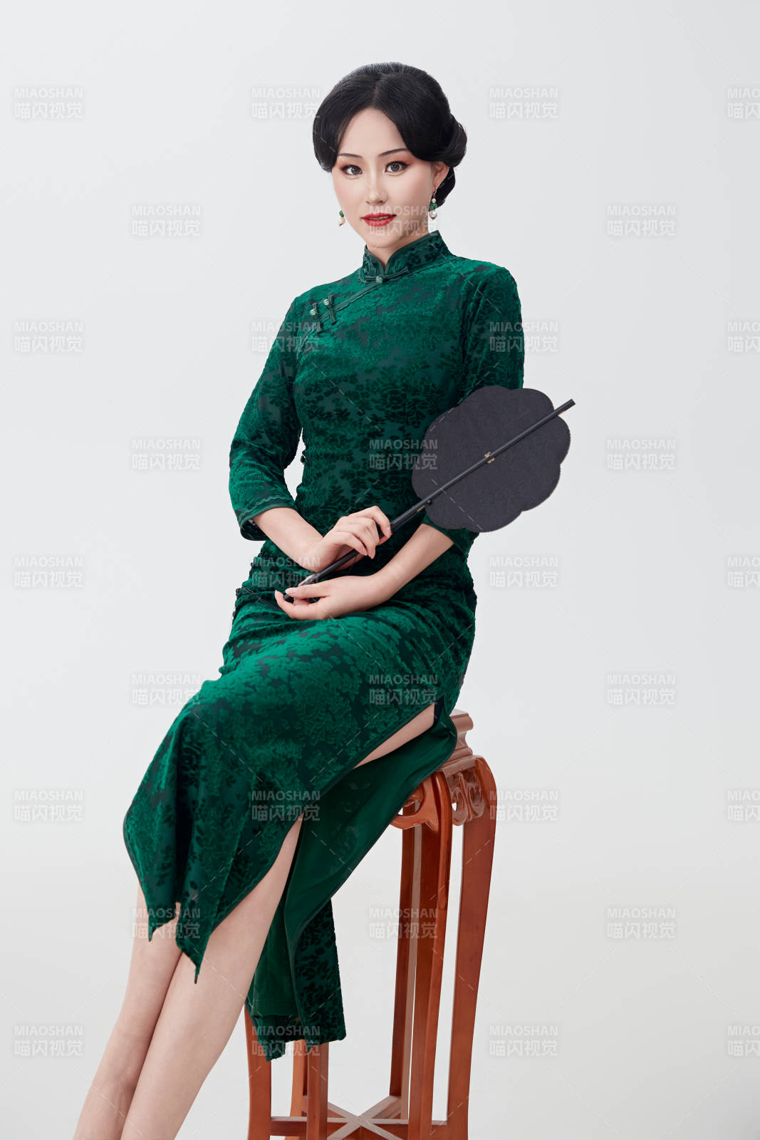 手拿纸扇身着中式旗袍坐在凳子上的美女图片