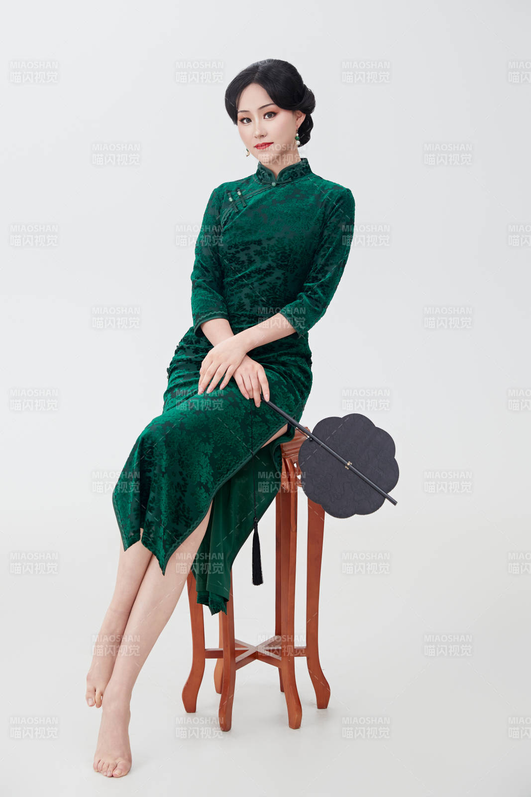 手拿纸扇身着中式旗袍坐在凳子上的美女图片