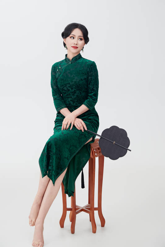 手拿纸扇身着中式旗袍坐在凳子上的美女图片