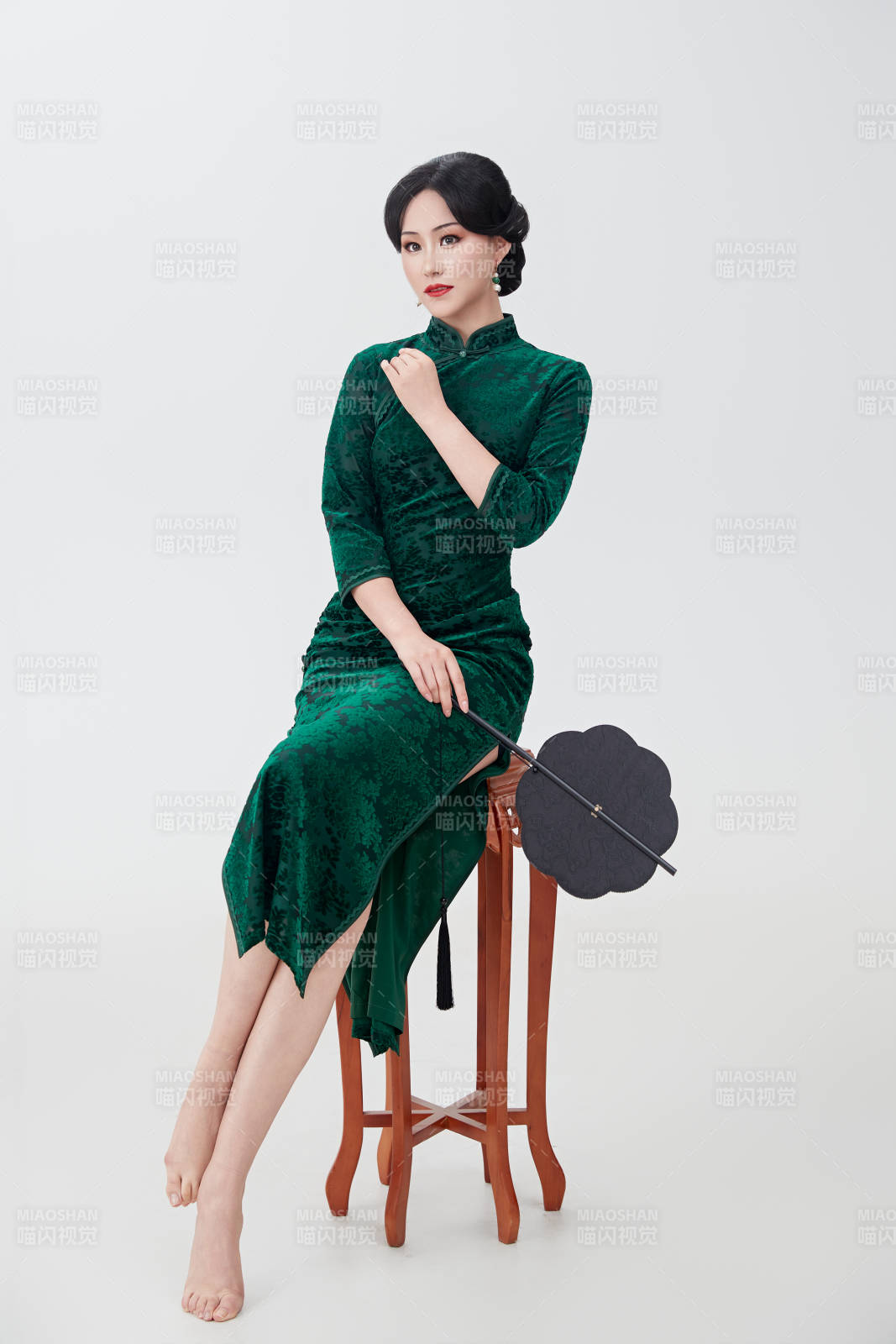 手拿纸扇身着中式旗袍坐在凳子上的美女图片