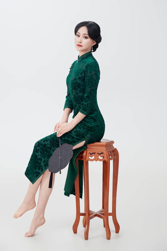 手拿纸扇身着中式旗袍坐在凳子上的美女图片