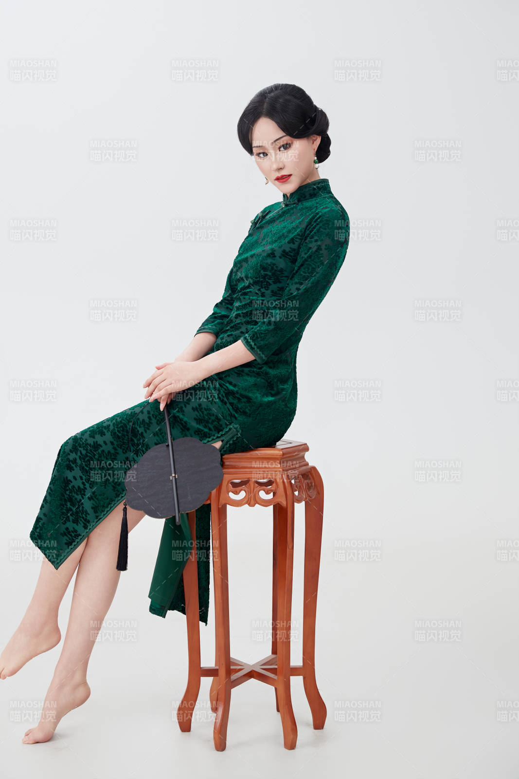 手拿纸扇身着中式旗袍坐在凳子上的美女图片