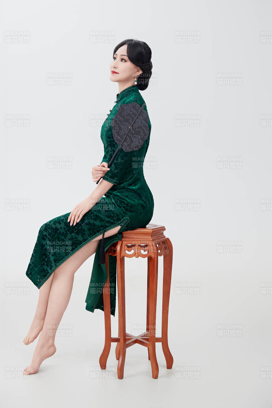 手拿纸扇身着中式旗袍坐在凳子上的美女图片