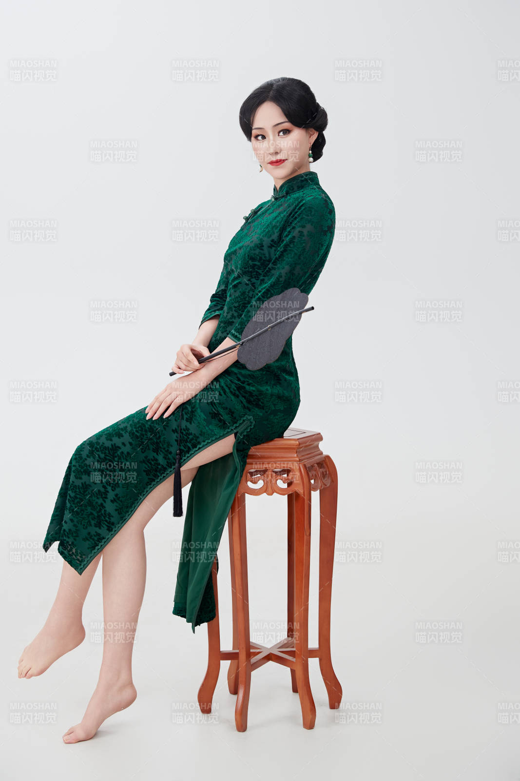 手拿纸扇身着中式旗袍坐在凳子上的美女图片