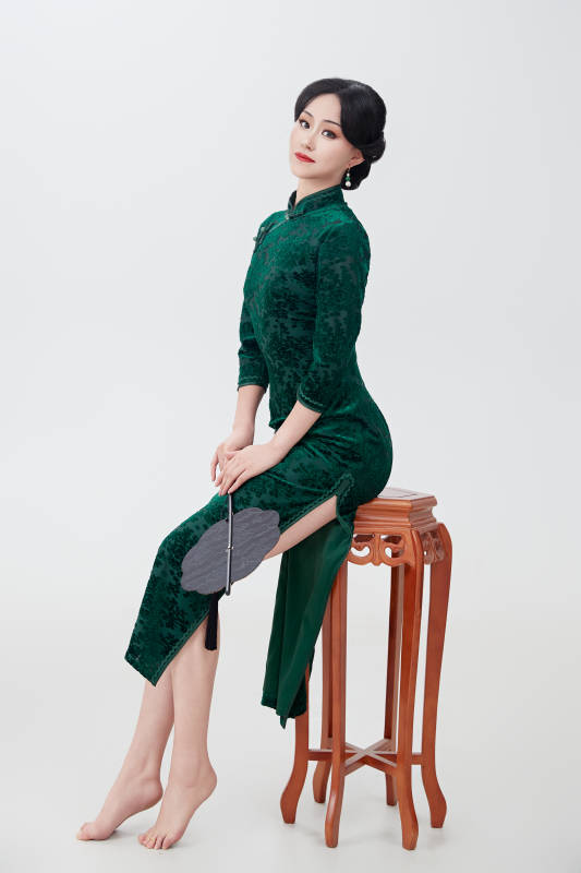 手拿纸扇身着中式旗袍坐在凳子上的美女图片