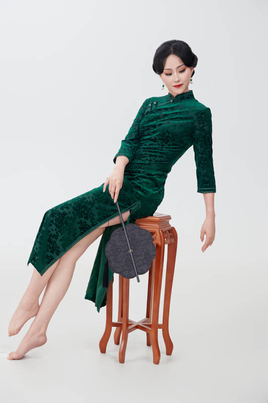 手拿纸扇身着中式旗袍坐在凳子上的美女图片