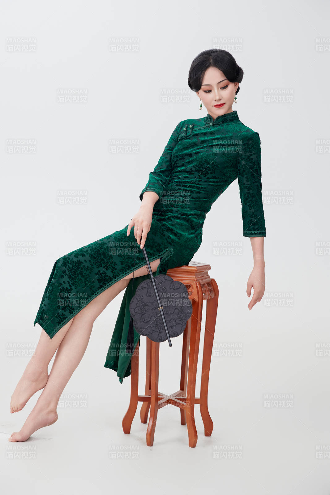 手拿纸扇身着中式旗袍坐在凳子上的美女图片