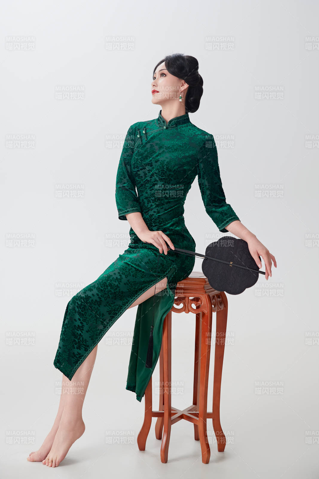 手拿纸扇身着中式旗袍坐在凳子上的美女图片