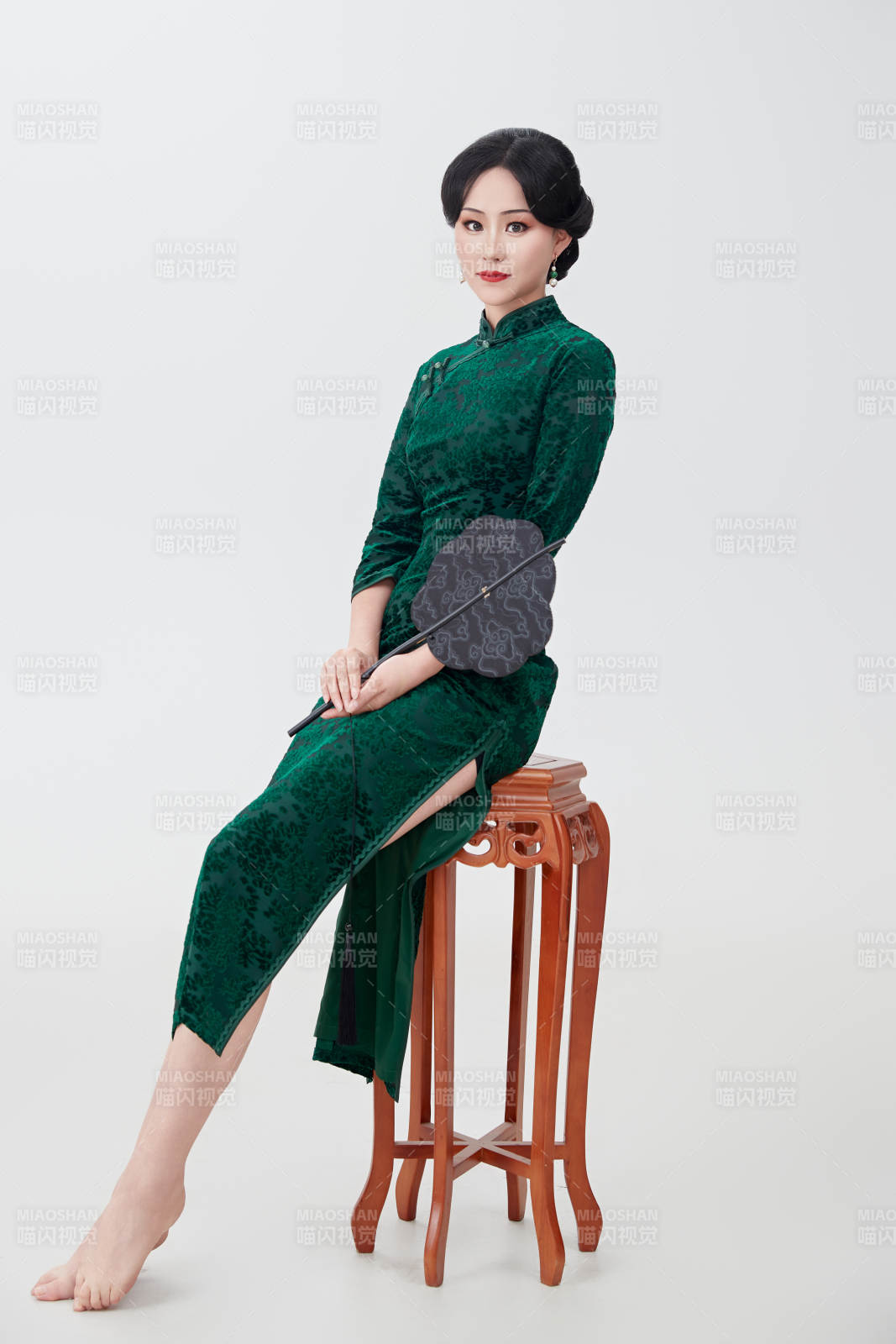 手拿纸扇身着中式旗袍坐在凳子上的美女图片