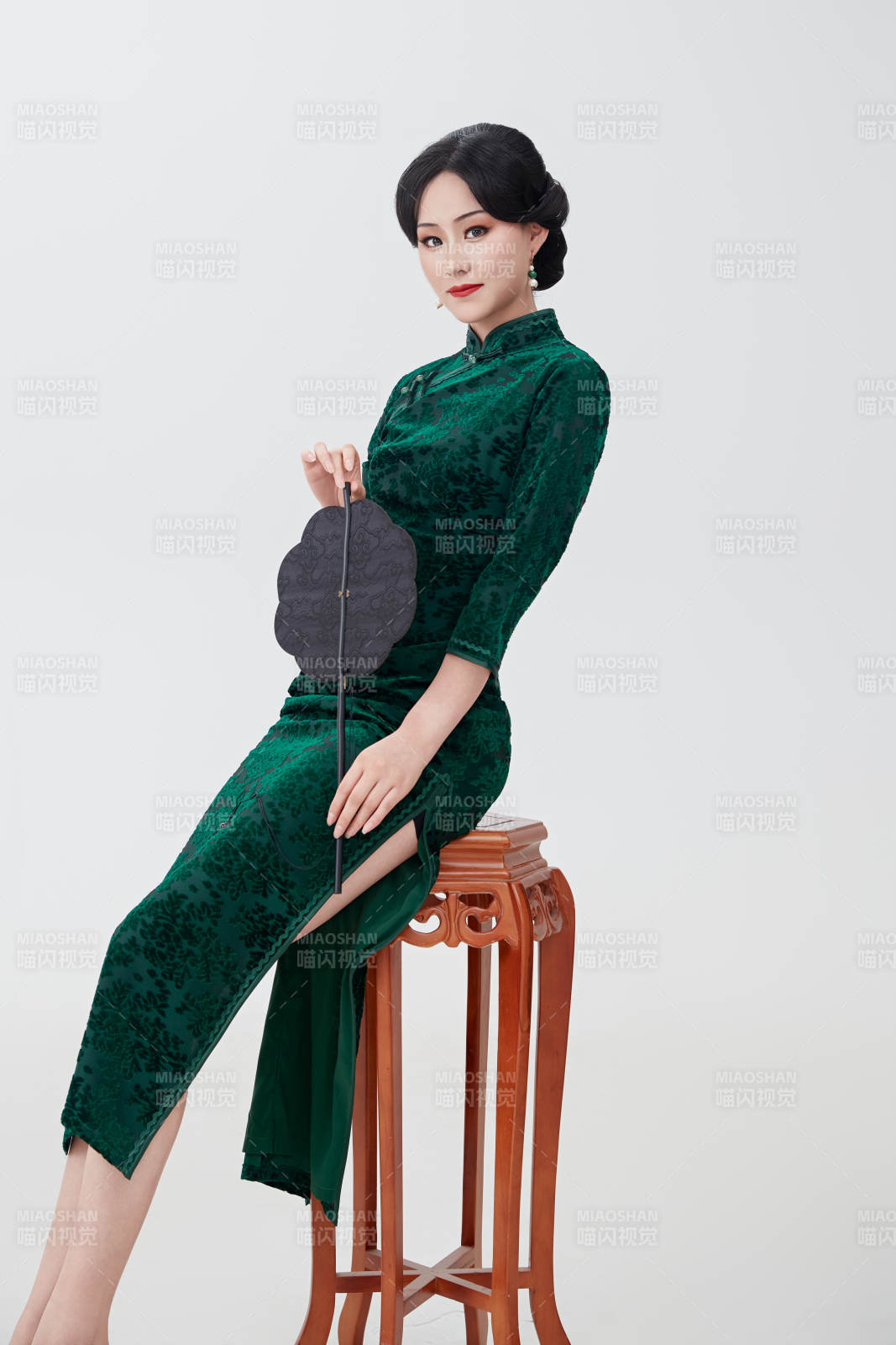 手拿纸扇身着中式旗袍坐在凳子上的美女图片