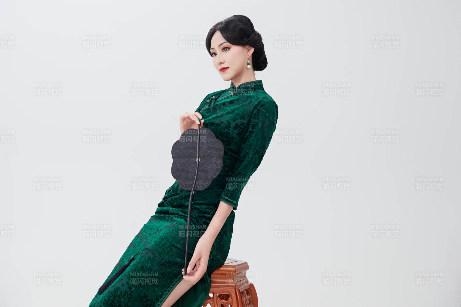 手拿纸扇身着中式旗袍坐在凳子上的美女图片