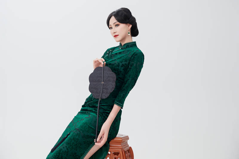 手拿纸扇身着中式旗袍坐在凳子上的美女图片