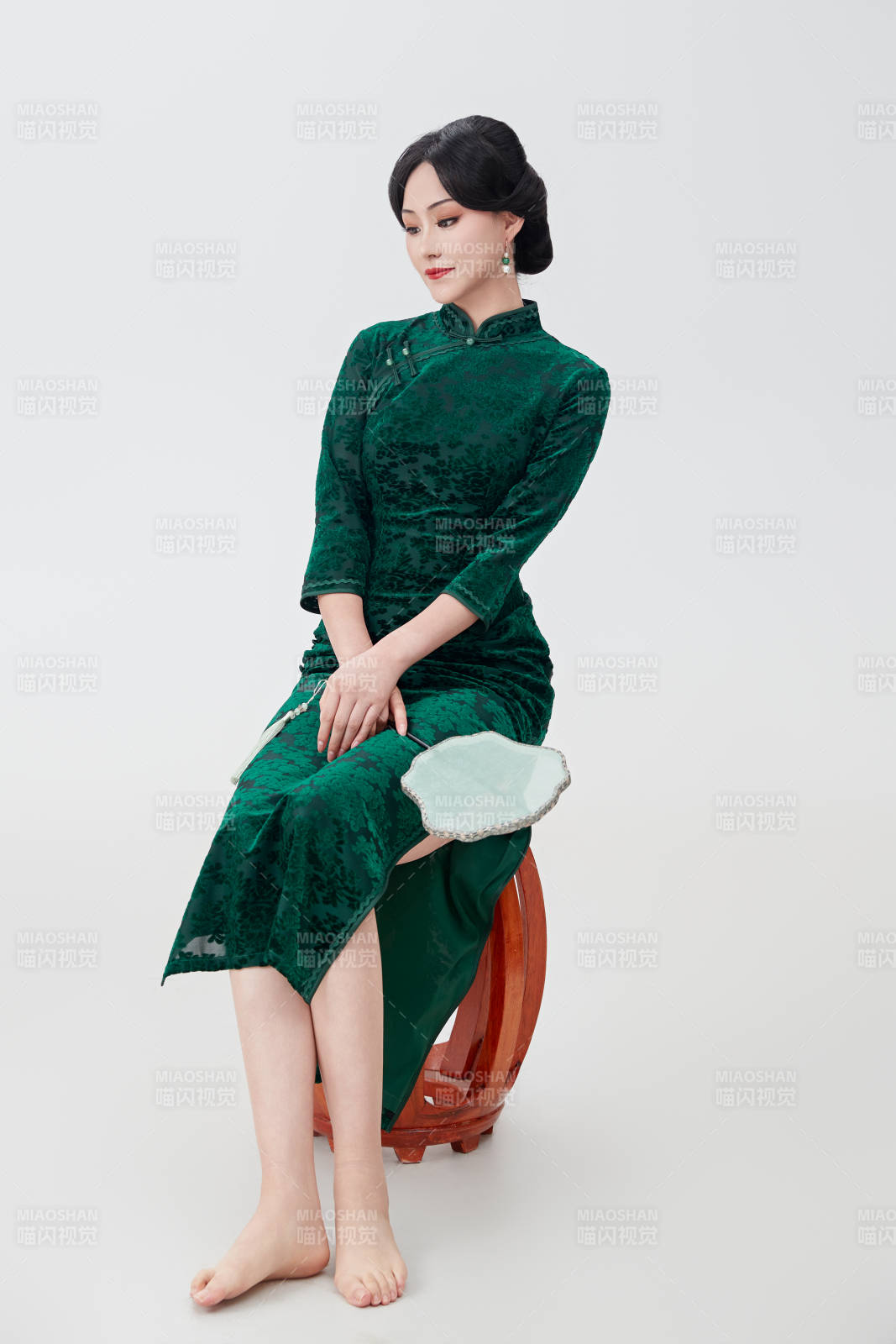 手拿纸扇身着中式旗袍坐在凳子上的美女图片