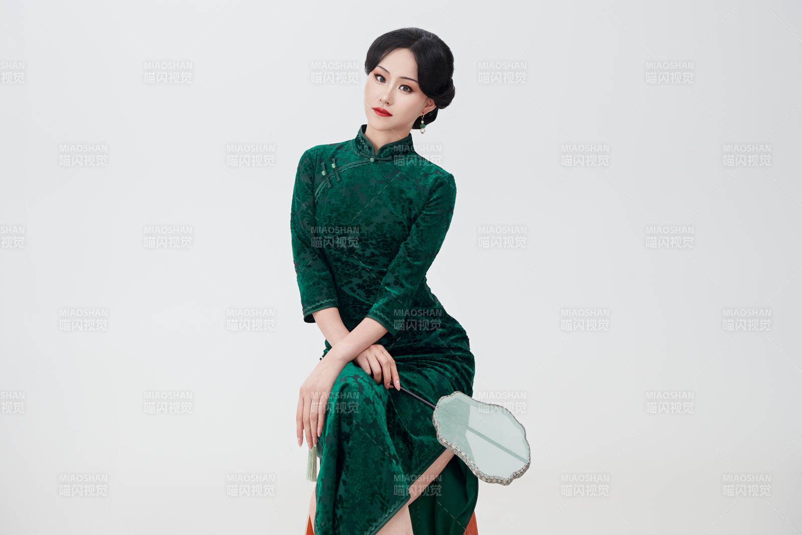 手拿纸扇身着中式旗袍坐在凳子上的美女图片