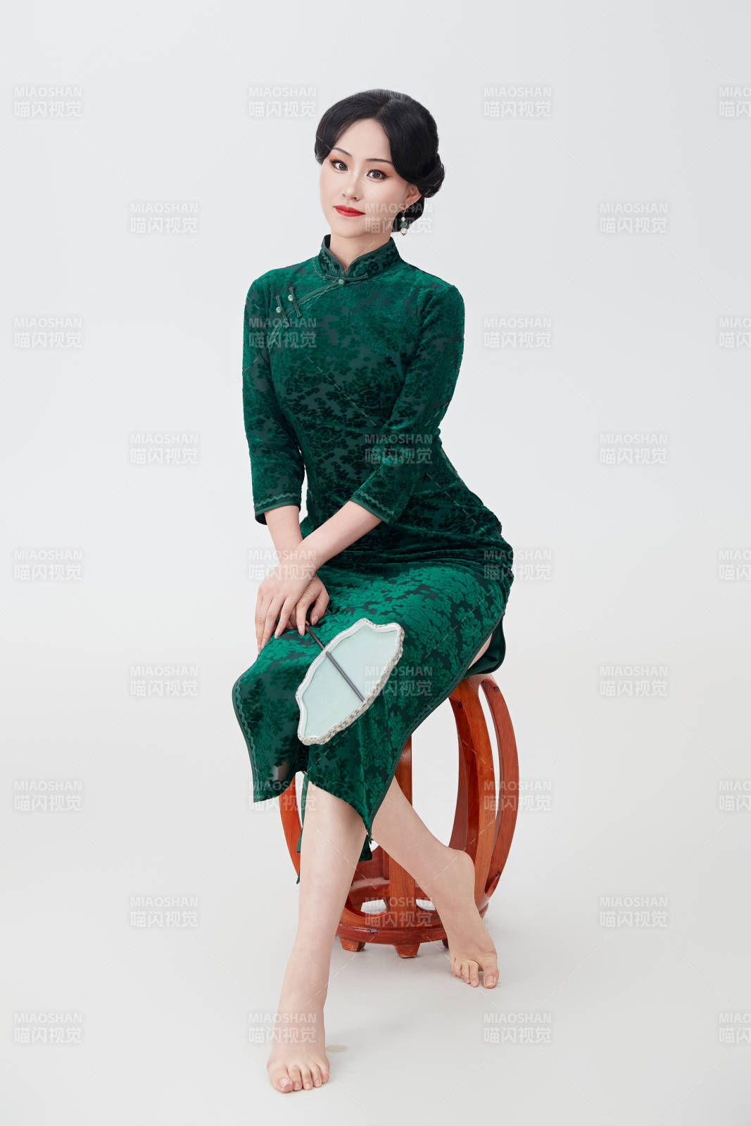 手拿纸扇身着中式旗袍坐在凳子上的美女图片