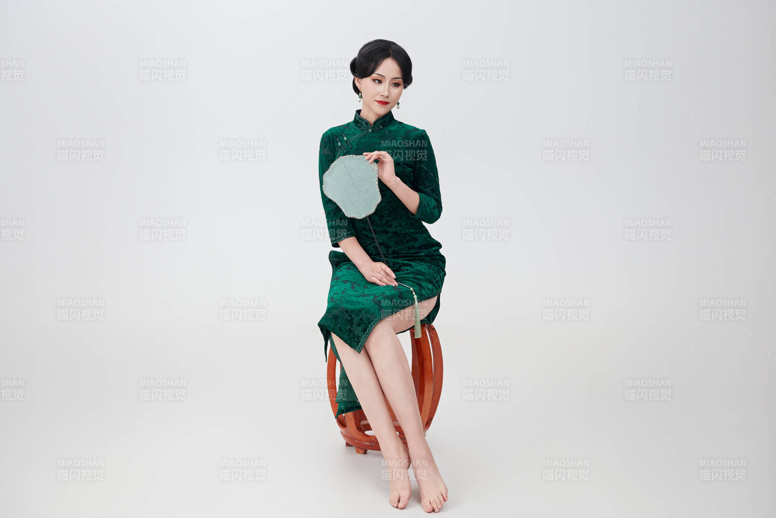 手拿纸扇身着中式旗袍坐在凳子上的美女图片