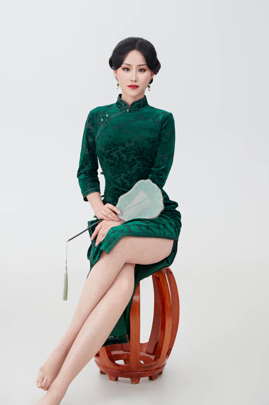 手拿纸扇身着中式旗袍坐在凳子上的美女图片