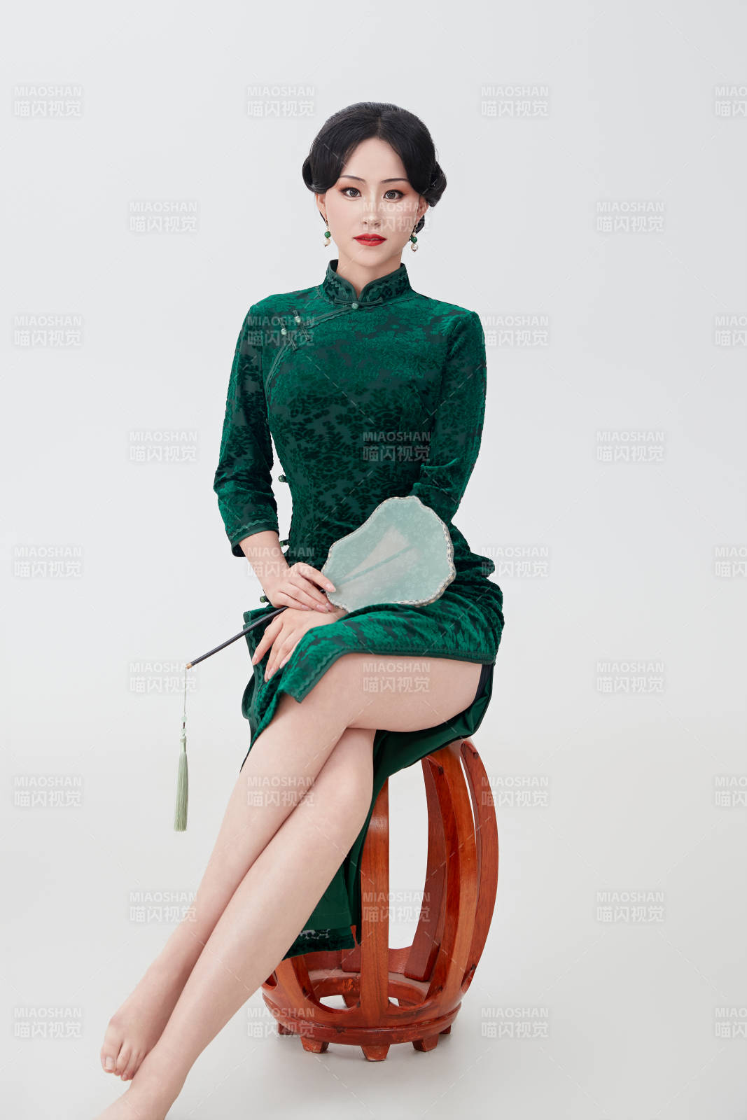 手拿纸扇身着中式旗袍坐在凳子上的美女图片