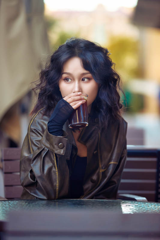 身穿复古皮衣在户外喝咖啡的东方美女图片