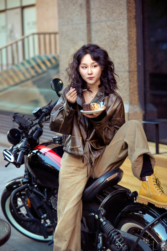 户外在复古机车上品尝甜点的亚洲美女图片