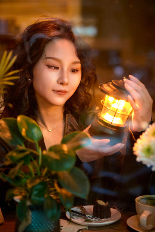 傍晚坐在咖啡店里享受咖啡蛋糕的美女图片