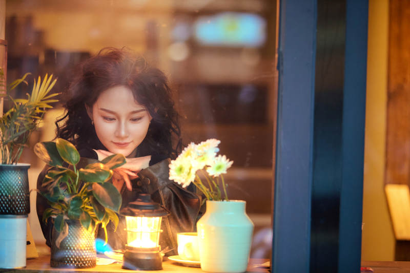 傍晚坐在咖啡店里享受咖啡蛋糕的美女图片