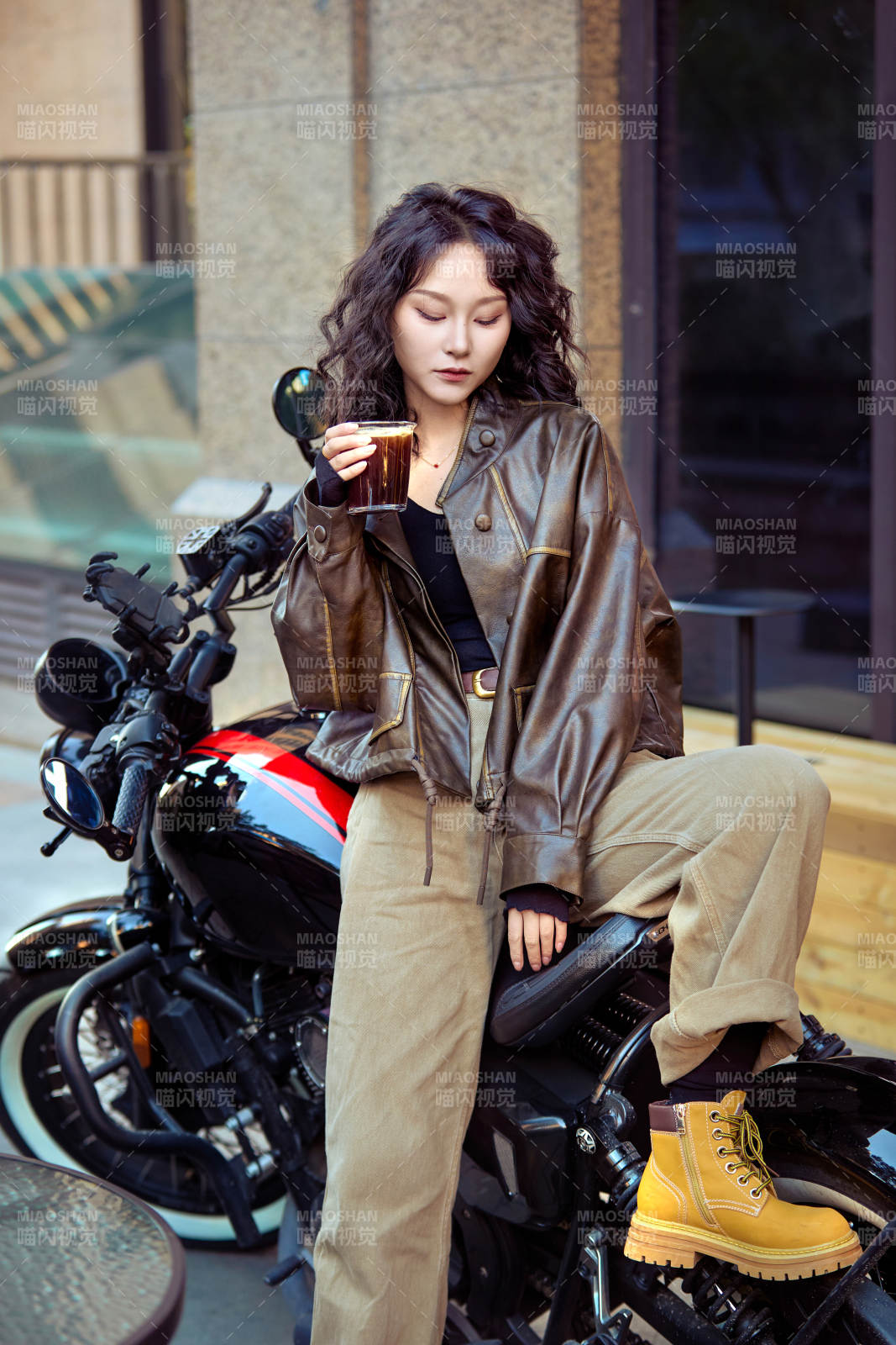 手拿冰美式咖啡坐在摩托上的亚洲美女图片