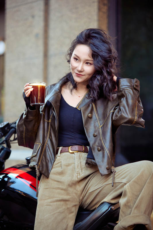 手拿冰美式咖啡坐在摩托上的亚洲美女图片