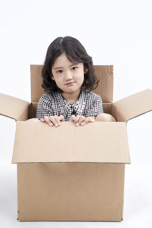 躲在纸箱中玩耍的调皮可爱亚洲小女孩儿童图片
