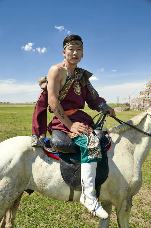 草原那达慕大会上骑着马的蒙古人图片
