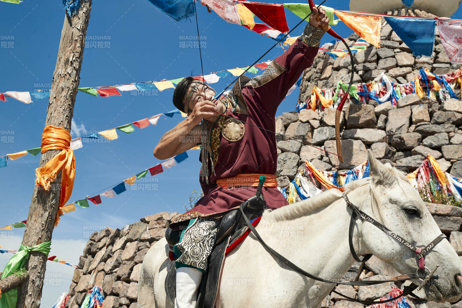 草原敖包前骑马拉弓射箭的蒙古弓箭手图片